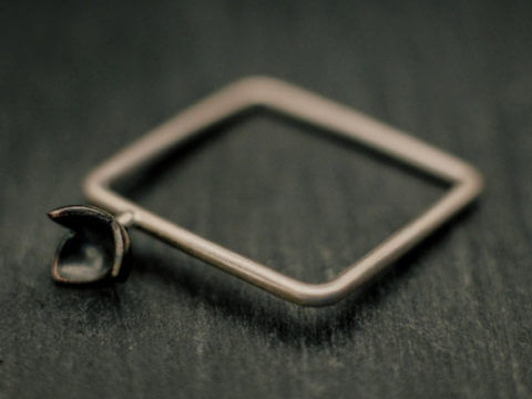 Bague carrée en fil d'argent rond, avec une petite fleur à trois pétales soudée en relief sur le corps de bague