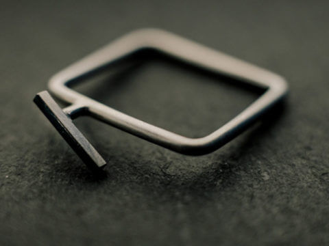 Bague carrée en fil d'argent rond, avec, en relief, une petite tige de section carrée soudée légèrement de biais.