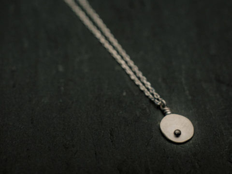 pendentif en argent composé d'une pastille ovale martelée ornée d'une petite bille, monté sur chaîne.