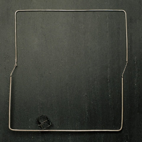 Collier carré en argent, articulé grâce à deux petites chaines de chaque côté. Cube en argent texturé et noirci.