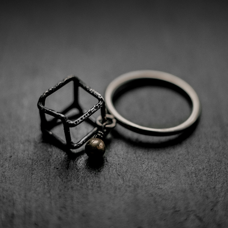 bague composée d'un anneau en argent, d'un cube mobile en fil d'argent noirci et d'une bille en or mobile