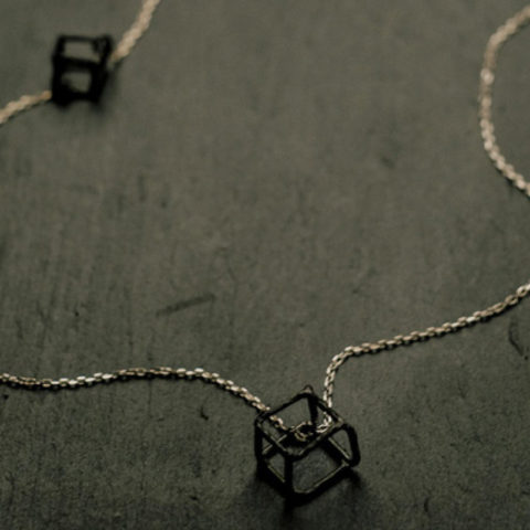 Sautoir sur chaîne en argent avec trois cubes en argent texturé et noirci (deux petits fixes et un grand mobile).