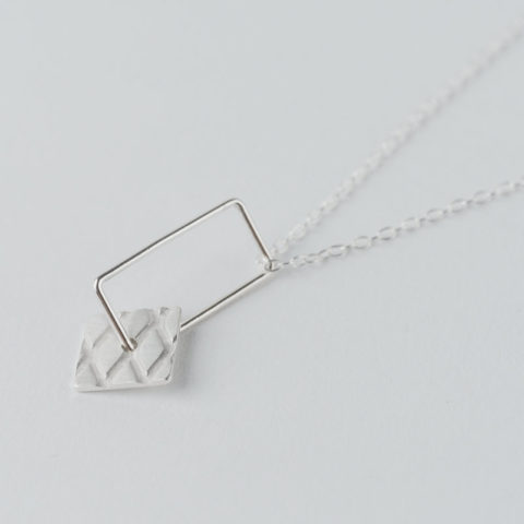 petit pendentif en argent composé d'un rectangle en fil et d'un carré avec motif grillage incrusté, monté sur chaîne.