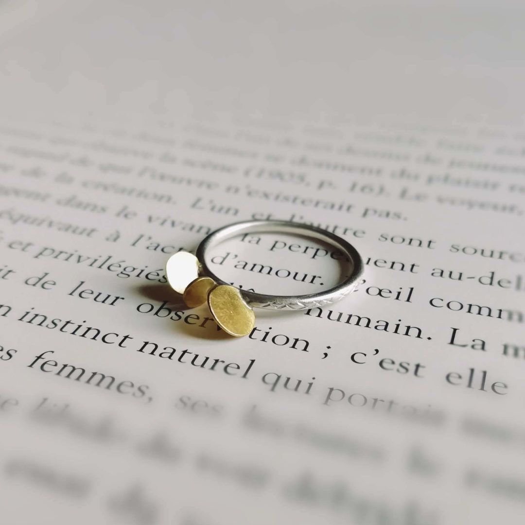 anneau fil rond en argent ciselé sur lequel sont soudées de manière irrégulière trois pastilles en laiton martelé.