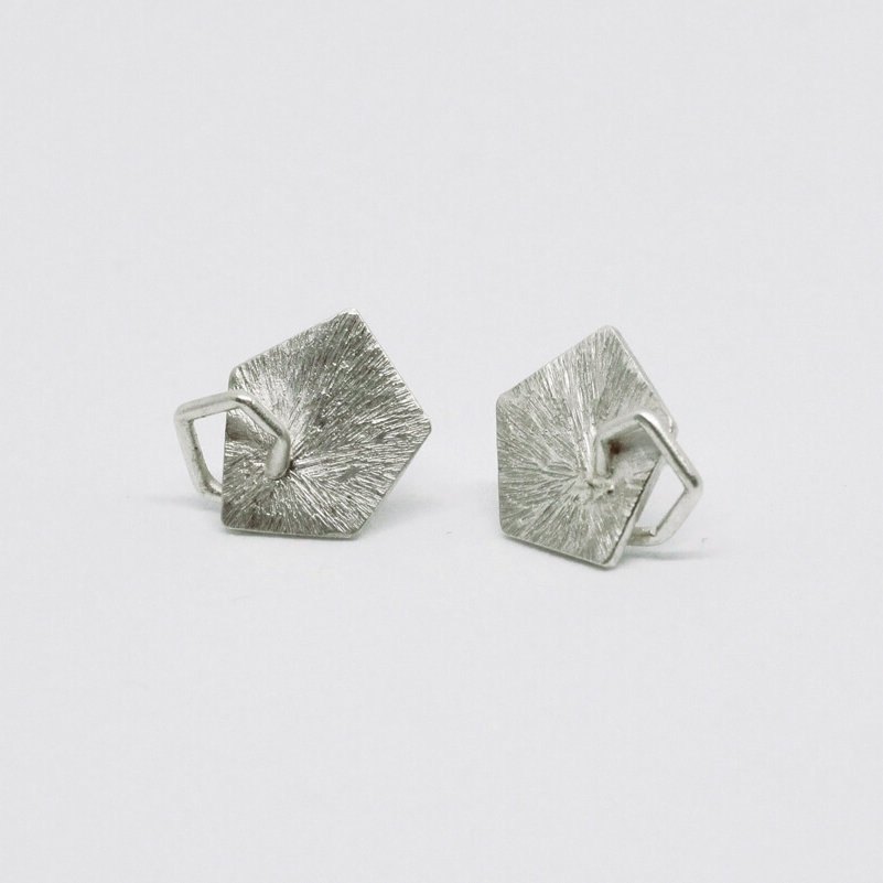 Boucles d'oreilles puces en argent composées de pastilles géométriques de formes pentagonales à la surface striée sur lesquelles sont soudées de petits pentagones en fil d'argent